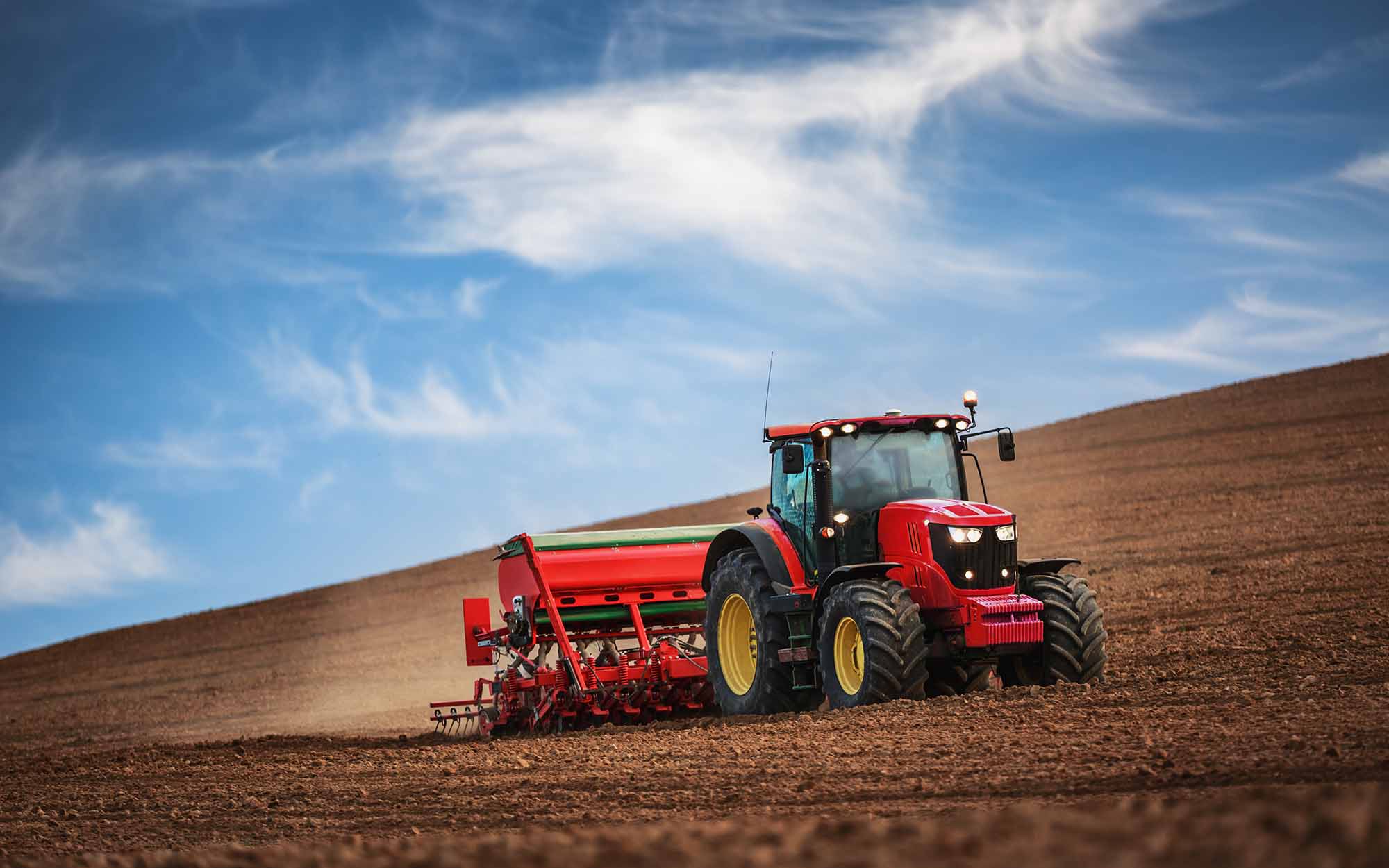 Farmer with tractor seeding crops at field