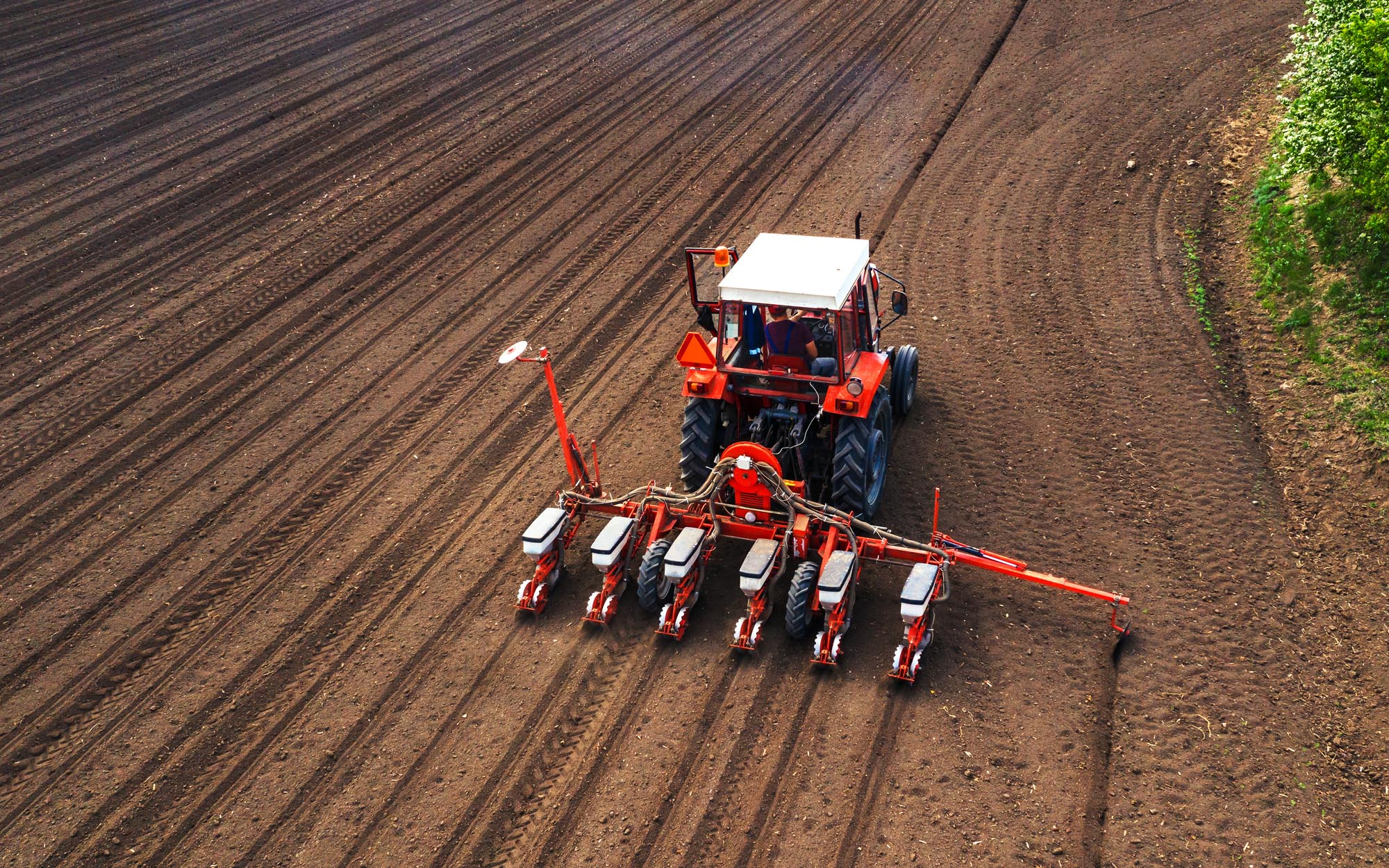 Aerial view of tractor with mounted seeder performing direct seeding?